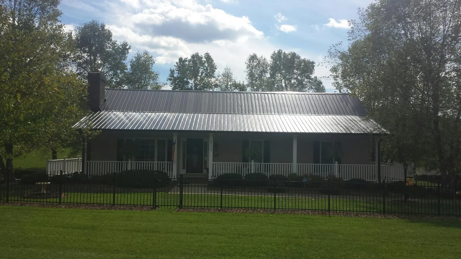 Gray metal roof on a brick ranch with a full width front porch — Gutter Guard Installation work by our crew in Appleton